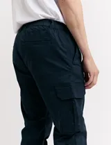 Pantalón de gabardina verde militar, corte cargo con bolsillos laterales con fuelle y tobillos ajustados con elástico.