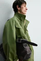 Parka estilo militar color verde, de corte relaxed fit, cuello subido y manga larga. Cuenta con bolsillos de plastrón con solapa en el pecho y en la cadera, cintura ajustable con cordón interior y cierre frontal con cremallera oculta por solapa con botones a presión.
