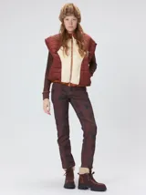 Chaleco de corte cuadrado con diseño bicolor en tonos terracota y crema. Presenta cierre frontal metalizado, parches de nylon en el pecho, interior forrado en corderito y cordón ajustable en el ruedo.