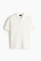 Remera polo de manga corta en punto texturizado de peso medio, color blanco, con cuello, tapeta de botones y bajo recto. Corte ajustado que realza el contorno del cuerpo.