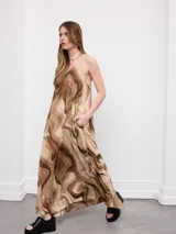 Vestido midi sin mangas, con estampado efecto mármol en tonos marrones y beige, cuello halter y detalle de choker incorporado.