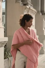 Ruana tejida en telar con lana merino 100% natural, color rosado, con flecos en los bordes.