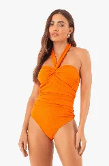 Traje de baño enterizo color naranja, marca Silvia Schaefer, con escote halter, copas extraíbles y protección solar UV50+.