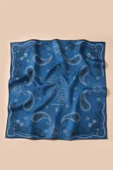 Pañuelo cuadrado de seda color azul con estampado de estilo paisley y flores blancas. Presenta bordes con terminaciones a mano y el logo de la marca en el centro.