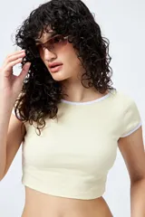 Top corto negro de punto acanalado con escote redondo, mangas cortas y ribetes blancos en cuello y mangas.