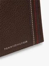Billetera plegable Tommy Hilfiger de piel granulada color marrón, con diseño compacto, compartimento interior para billetes, múltiples ranuras para tarjetas y detalles distintivos de la marca con costuras tricolores y logo metálico.