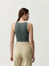 Musculosa de tejido acanalado color verde militar, con cuello redondo alto y diseño al cuerpo. Presenta una pequeña etiqueta decorativa en el centro del pecho.