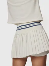Falda tipo skort con diseño plisado, cintura alta elástica con detalle de rayas horizontales en contraste. Incluye short integrado con bolsillo funcional, confeccionada en tejido técnico de secado rápido.