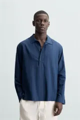 Camisa polo de manga larga con cierre frontal de botones, confeccionada en tejido con textura de rayas verticales sutiles.