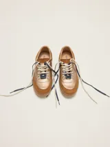 Championes de cuero metalizado color bronce con detalles en descarne marrón, cordones bicolores y ganchos metálicos para los cordones.