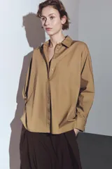 Camisa de corte amplio confeccionada en algodón, con cuello solapa, manga larga con puños y cierre frontal con botones ocultos bajo solapa. Presenta un bolsillo frontal en el pecho.