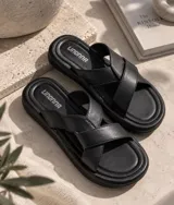 Sandalias planas con tiras cruzadas en color manteca y suela marrón con plataforma baja.