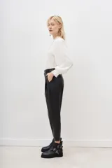Pantalón estilo capri de efecto cuero negro, con corte holgado y detalles de costuras geométricas en la parte delantera.