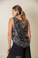 Blusa sin mangas confeccionada en tela cubierta de lentejuelas doradas y plateadas, con escote redondo y corte holgado.