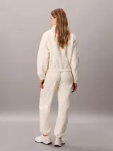 Jogger de tejido polar color blanco de Calvin Klein, con cintura elástica con cordón ajustable, bolsillos laterales con cremallera y puños elásticos en los tobillos.