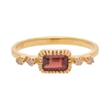 Anillo dorado con piedra central rectangular color borgoña y dos diamantes circulares a cada lado.