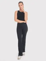 Top crop sin mangas de color negro, confeccionado en tejido acanalado con cuello redondo. Presenta un diseño ajustado al cuerpo con una pequeña abertura en la espalda y una cinta decorativa.