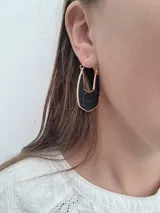 Par de aros colgantes con forma geométrica, con interior de cuero sintético negro con textura de piel de cocodrilo y borde dorado.