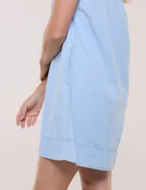 Vestido corto de lino color celeste con cuello camisero, escote en V, mangas cortas, bolsillos laterales invisibles y silueta holgada.