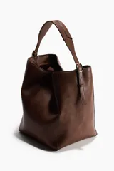 Cartera shopper de diseño slouchy en color marrón, con correa ajustable en la parte superior y detalles de tiras colgantes en los laterales con hebillas metálicas.