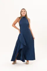 Vestido largo azul de tafeta con textura corrugada, cuello halter, espalda descubierta y falda amplia con tajo lateral y volados.