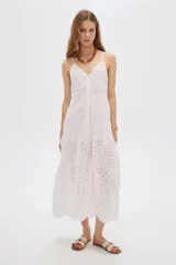 Vestido midi blanco de algodón con diseño broderie, tirantes finos, escote en V y cierre frontal con botones.