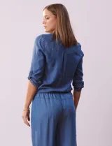 Blusa celeste de tencel, marca Alex & Parker. Cuello a la base, escote en V y abertura central con botones. Delantera con bolsillos. Largo de manga regulable con presilla y botón. Terminación de ruedo con nudo.