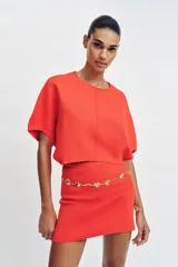 Falda corta de punto con cintura elástica y diseño en evasé de color rojo.