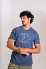 Remera de cuello redondo y manga corta, color azul, con estampado circular en el pecho que incluye el logo de la marca Original Penguin.