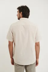 Camisa sport de manga corta, confeccionada en una mezcla de lino y algodón. Presenta cuello clásico, cierre frontal con botones de coco y un bolsillo aplicado en el pecho.