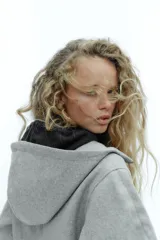 Cazadora de estilo deportivo con capucha ajustable, cierre frontal de doble cremallera y mangas abullonadas con puños elásticos. Presenta bolsillos delanteros y bajo elástico.