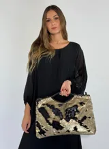 Bolso de mano tipo clutch con lentejuelas doradas y negras formando un diseño abstracto. Tiene asa corta de cuero sintético negro.