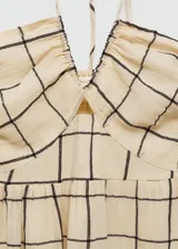 Vestido largo de algodón con estampado de cuadros oscuros sobre fondo beige. Presenta diseño evasé, cuello halter con tirantes finos y detalle de panel nido de abeja en la parte superior.