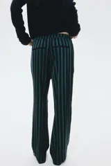 Pantalón de mujer a rayas verticales azul marino y verde, con cintura elástica, bolsillos laterales discretos y bolsillos traseros decorativos. Presenta piernas rectas con pliegues delanteros y traseros.