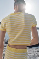 Top corto de punto con diseño a rayas horizontales en color amarillo y blanco, cuello redondo y manga corta.