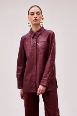 Camisa de cuero color borgoña, de corte recto, con cuello clásico, cierre frontal con botones, dos bolsillos con solapa en el pecho y bordado al tono en uno de ellos.