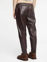 Pantalón de cuerina color negro con cintura elástica y cordón de ajuste. Presenta un corte tipo jogger con bolsillos laterales.