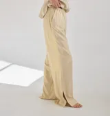 Pantalon de corte recto y tiro medio, confeccionado en lino, con cintura elastizada y tajos laterales en el ruedo.