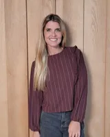 Blusa de manga larga color bordó con estampado de rayas verticales finas en color blanco. Presenta un diseño con volados en los hombros y puños elásticos.