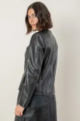 Campera de cuero color camel, con cuello redondo, cierre frontal y detalles de tachas metálicas en el cuello y bolsillos laterales.