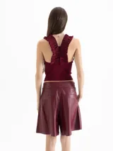 Top tejido de punto color negro, con ajuste al cuerpo, cuello redondo y volados decorativos en las sisas.