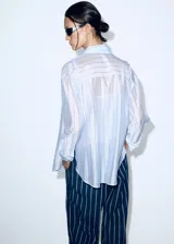 Camisa oversize de manga larga a rayas celestes y blancas, con cuello solapa camisero y cierre frontal de botones.