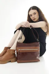 Cartera de cuero color beige, de diseño estructurado, con bolsillo frontal con cierre y detalles en cuero grabado con efecto reptil. Cuenta con correa ajustable para llevar al hombro o cruzada.