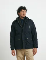 Campera de abrigo color verde militar, con capucha desmontable forrada, cierre frontal con cremallera y botones a presión. Cuenta con múltiples bolsillos: dos en el pecho con cierre, dos en la cintura con botones y un bolsillo en la manga. El interior está forrado para mayor calidez.