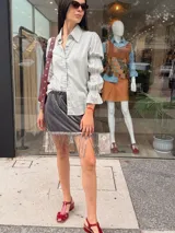 Mini falda de terciopelo gris con cintura elástica y borde inferior decorado con flecos de lentejuelas plateadas.