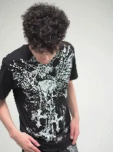 Remera negra de corte oversize con estampado frontal en blanco que presenta motivos góticos, incluyendo alas, cadenas y cruces.