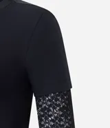 Blusa tipo baby look color negro, con cuerpo de algodón y mangas largas integradas de encaje con diseño floral. Presenta un diseño de superposición que simula una manga corta sobre la manga larga de encaje.
