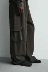 Pantalón cargo de corte relajado con efecto lavado, confeccionado en tejido de algodón. Presenta cintura elástica, bolsillos laterales de plastrón con solapa y bolsillos delanteros.