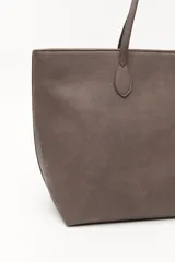 Cartera tipo tote de diseño minimalista y estructura flexible, confeccionada en material sintético con acabado mate. Cuenta con asas largas para llevar al hombro y un compartimento principal amplio.