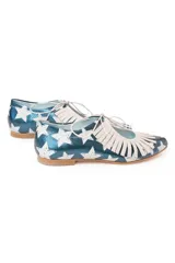 Zapato tipo blucher de cuero con acabado metalizado en color azul petróleo y estampado de estrellas blancas. Presenta un diseño con flecos decorativos en la parte frontal, cierre con cordones y suela plana de cuero.